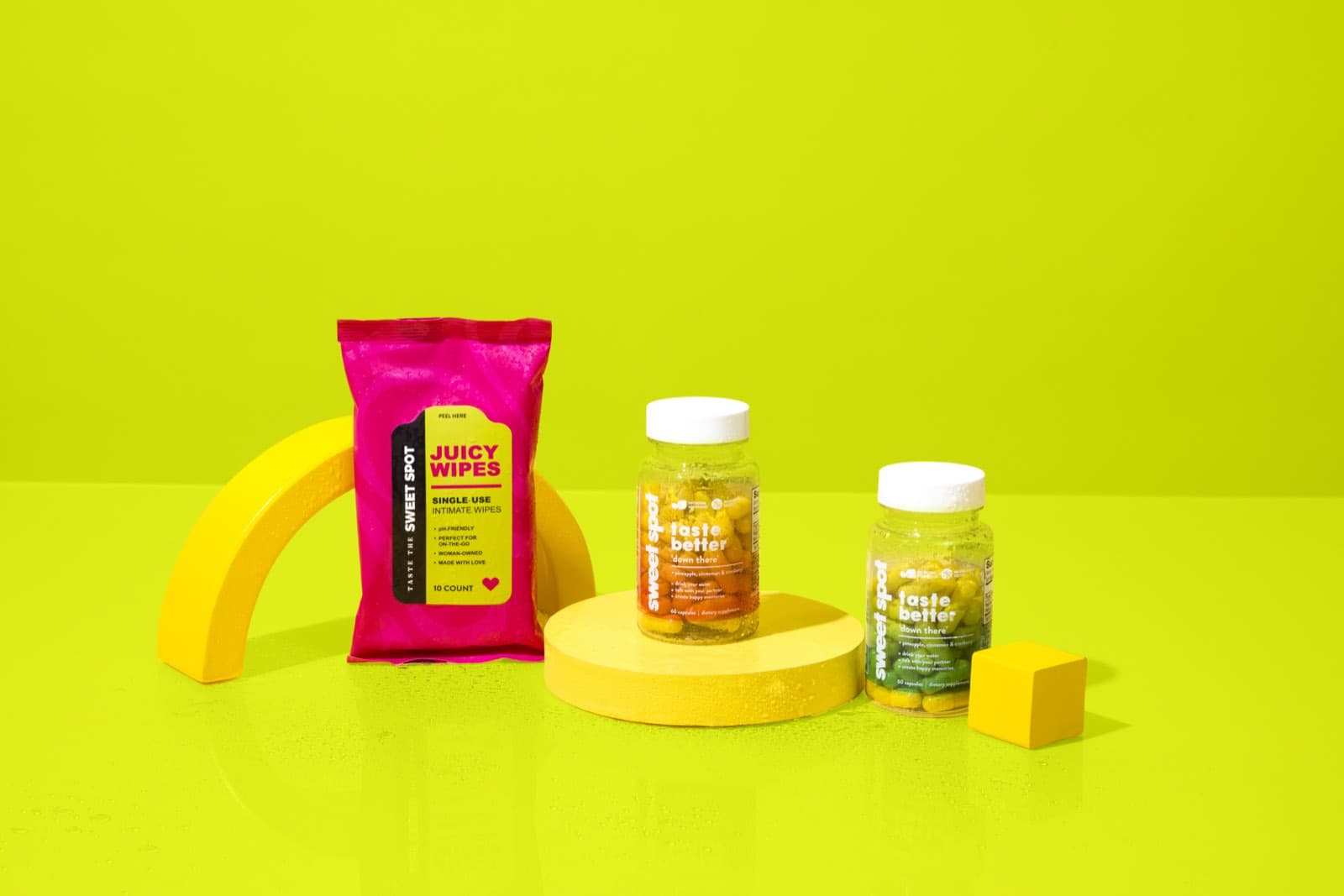 Juicy Wipes, For Her, and For Him on a lime set with a yellow arch