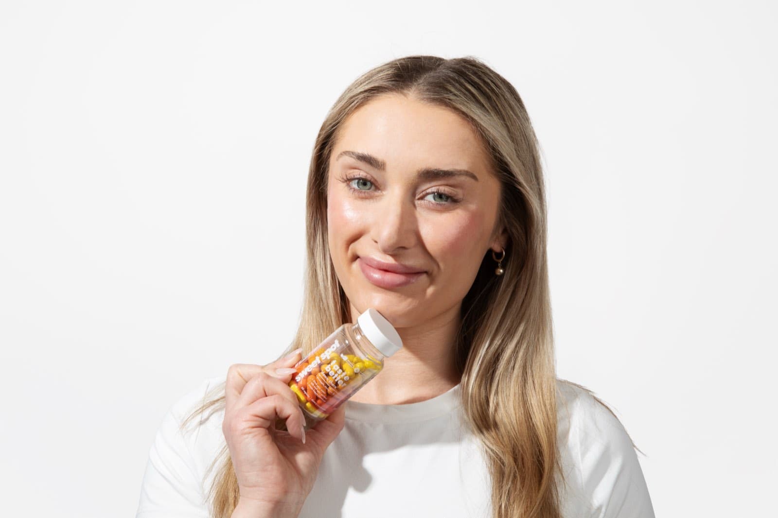 A woman in a white shirt holds a For Her bottle near her chin