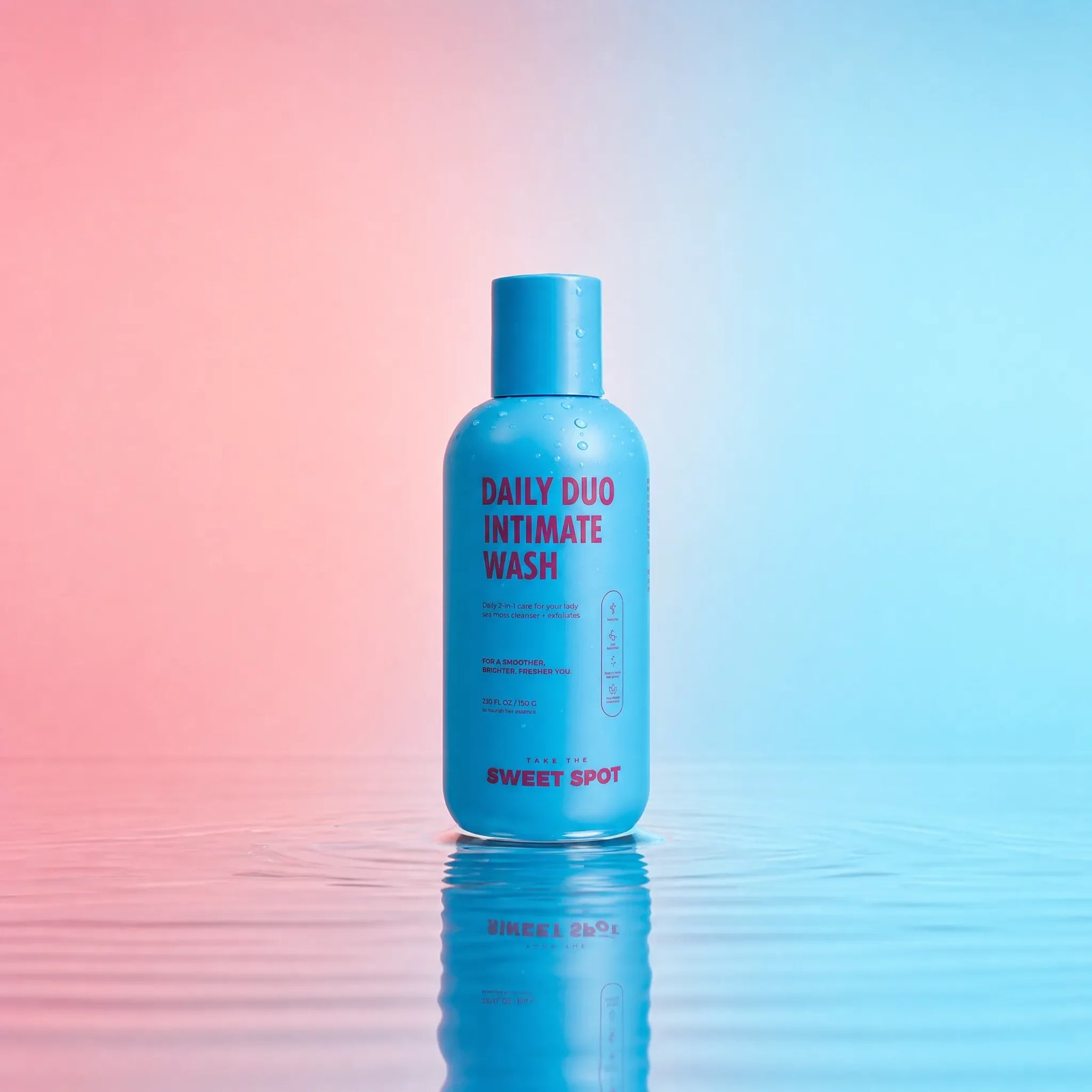A blue Daily Duo Intimate Wash bottle from Sweet Spot stands in shallow water with a reflection on a pink and blue background.