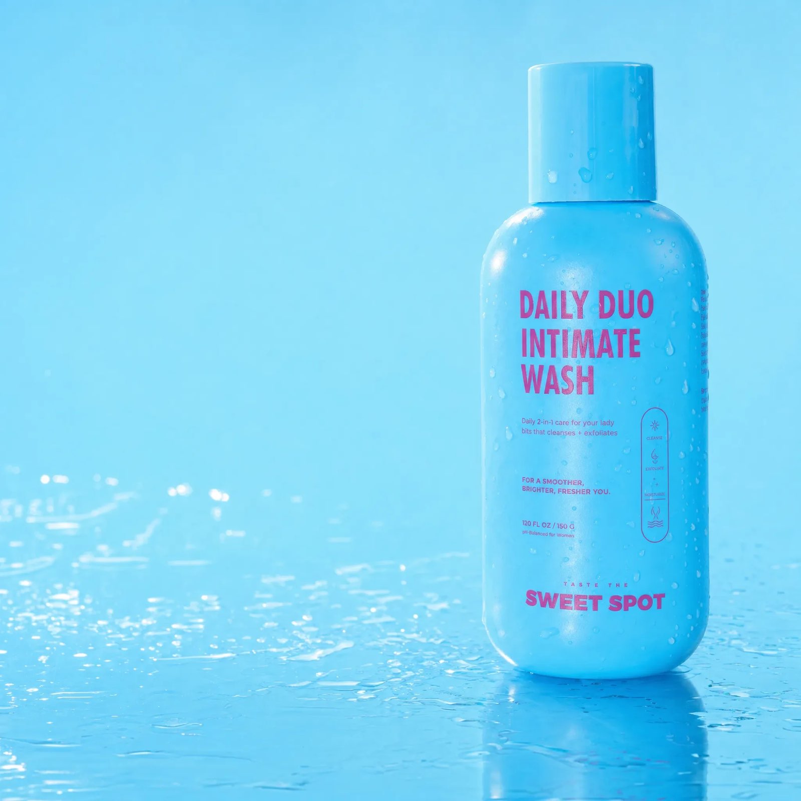 A blue Daily Duo Intimate Wash bottle covered in droplets stands on a wet blue surface, with Taste the Sweet Spot printed near the base.