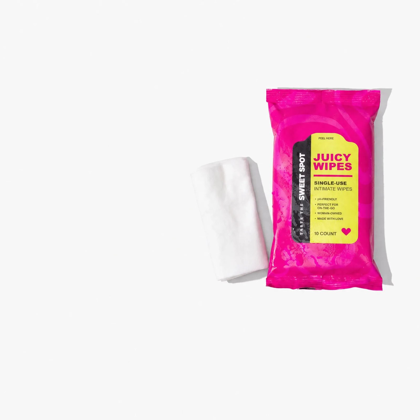 A pink Juicy Wipes packet labeled Taste the Sweet Spot lies on white next to a folded white wipe.