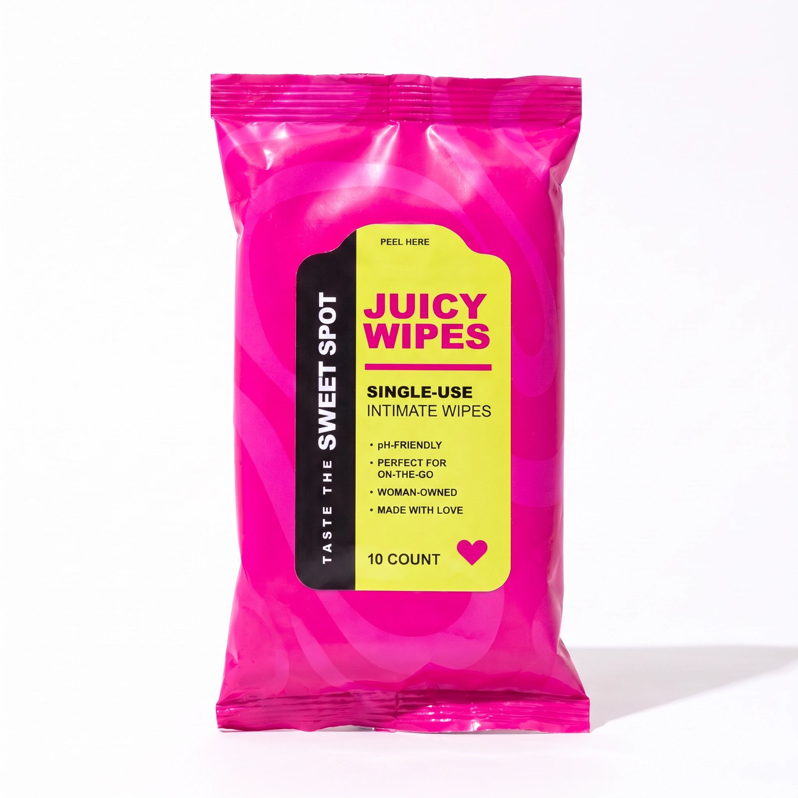 A bright pink Juicy Wipes packet faces the camera on white, its yellow label reading single-use intimate wipes and Taste the Sweet Spot.